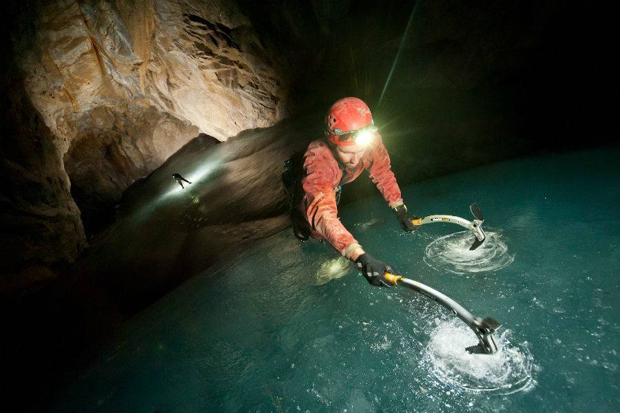 Guest using ice picks while exploring cave with Canmore Cave Tours.