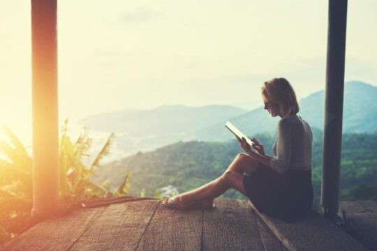 A person using a tablet overlooking a rainforest