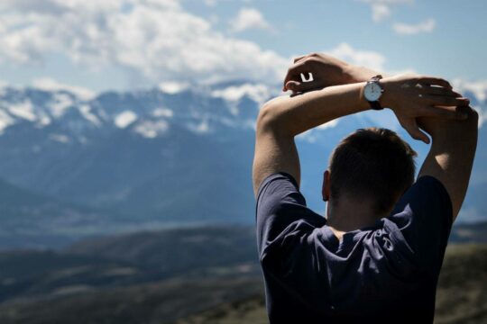 Man on a mountain top stretching