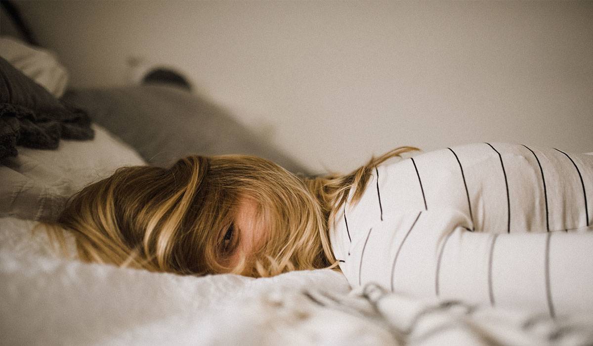 Woman laying down in bed resting her head on a pillow