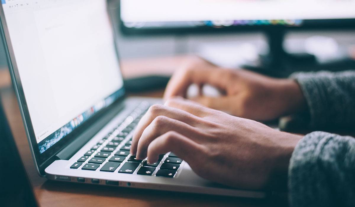 Pair of hands typing on a laptop keyboard