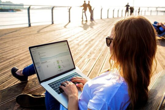 Woman sitting on a deck chair working on a laptop