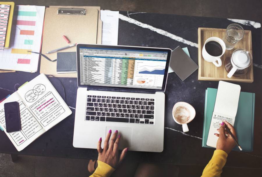 Person working on laptop surround by desk supplies