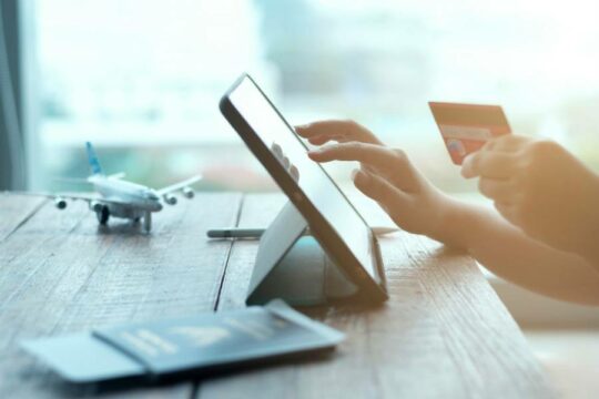 Woman holding credit card and tapping on tablet