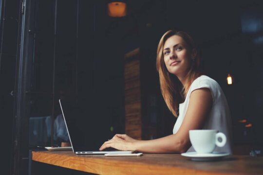 A person happily sitting at their laptop