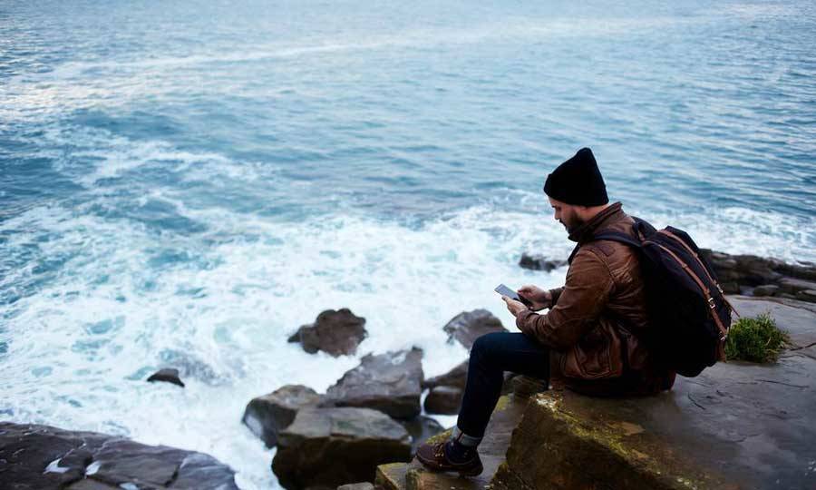 A person using their smartphone near a rocky beach