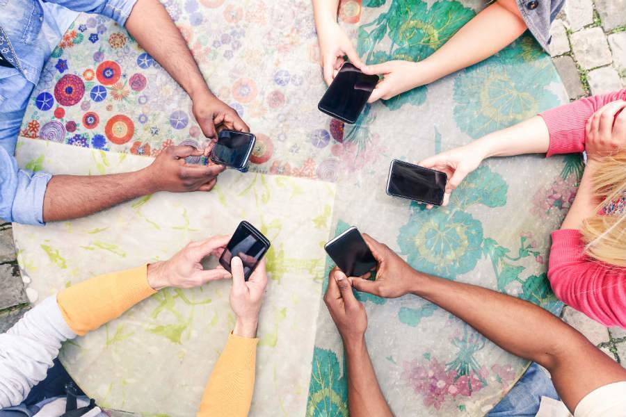 Five sets of hands holding cell phones