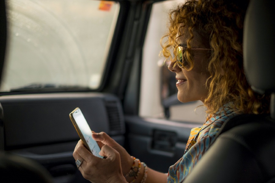 Curly haired woman checking social media in car