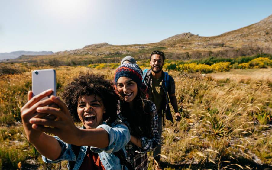Three hikers taking a selfie in grasslands. 