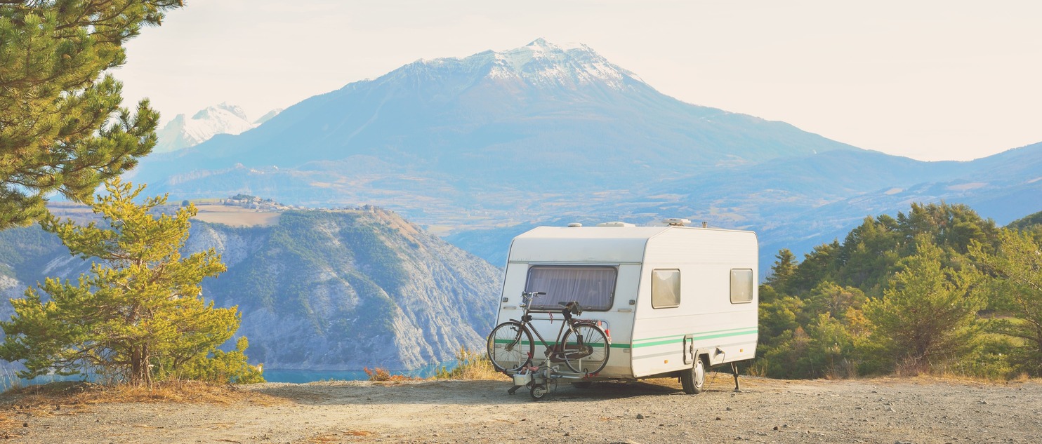 Caravan parked on a scenic mountain viewpoint, with attached bicycles, offering a serene camping experience surrounded by nature.