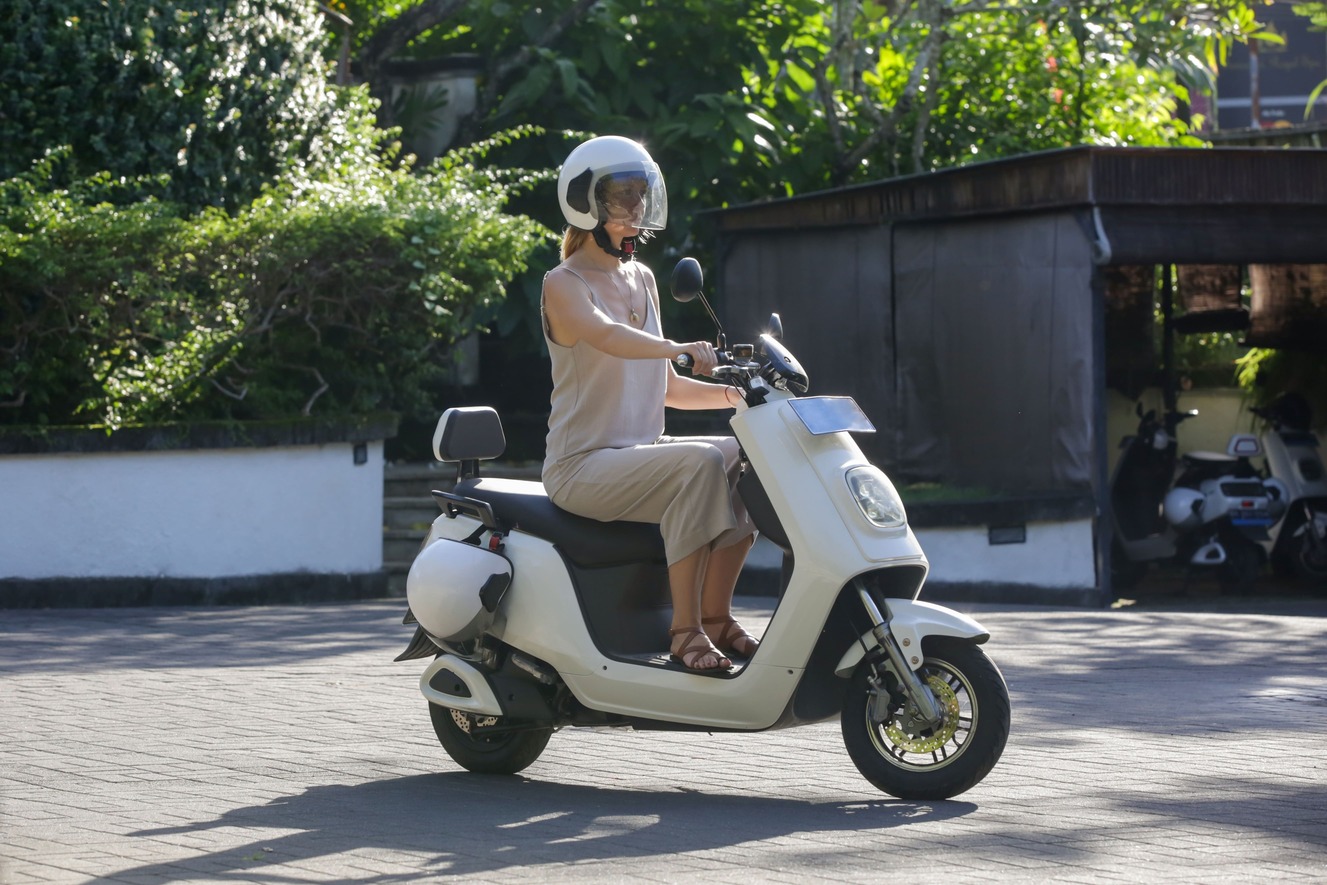 Woman riding a white electric scooter rented via a rental booking software.