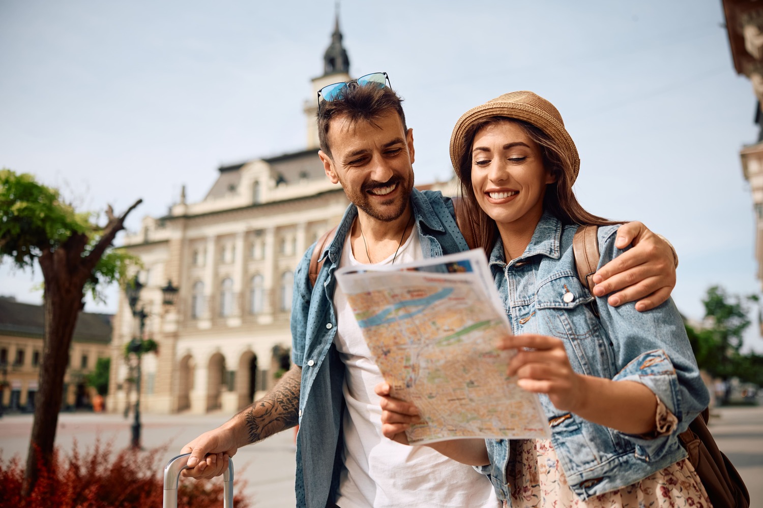 Smiling couple exploring a city with a map, representing seamless travel planning supported by top tour operator software.