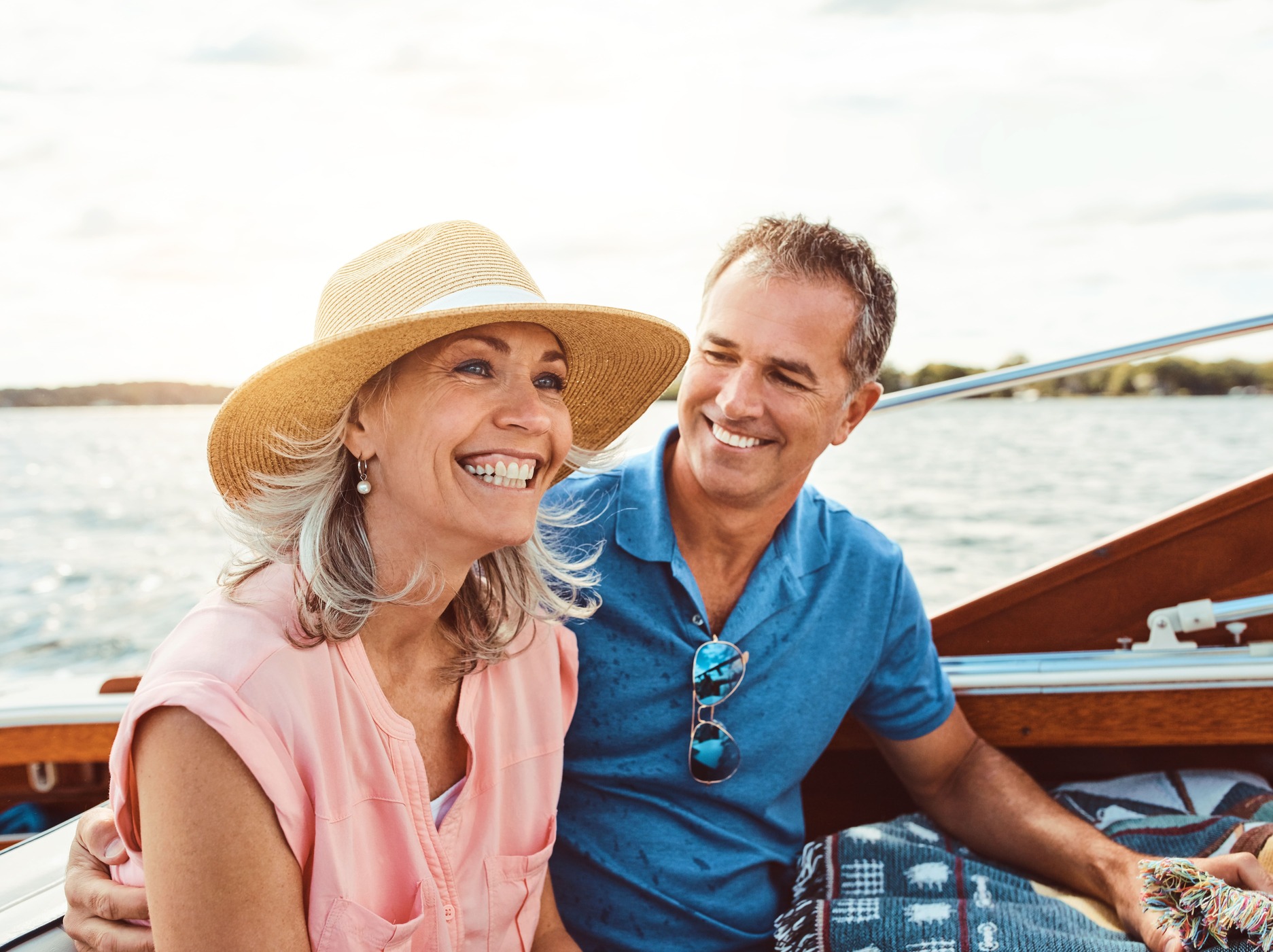 Smiling couple enjoying a relaxing boat ride on a sunny day, showcasing leisure and waterfront activities.